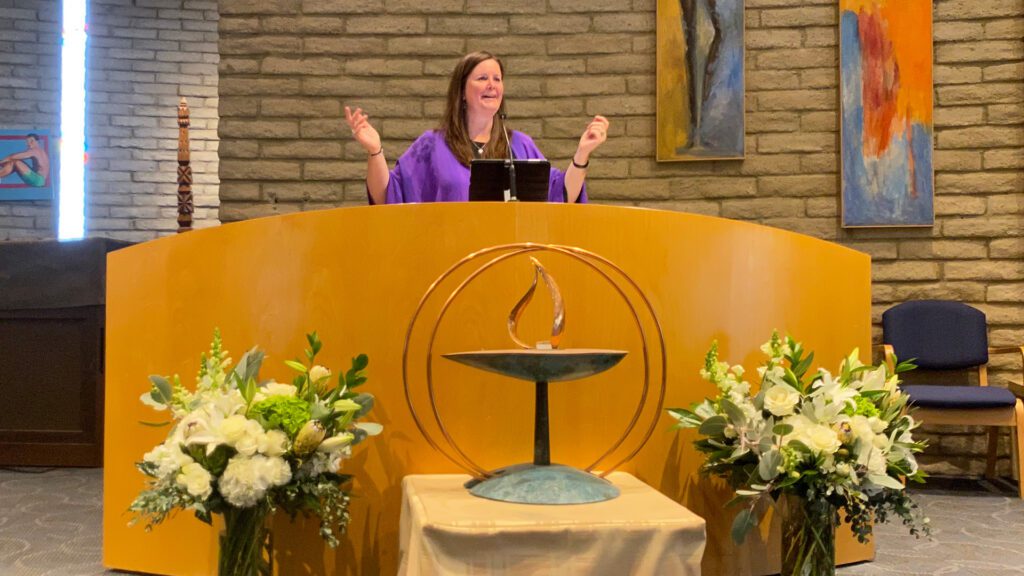 Rev Christine Dance behind altar, leading service in sanctuary