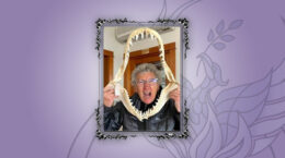 A picture of Jan Kaplan holding a fossil of teeth on a purple background