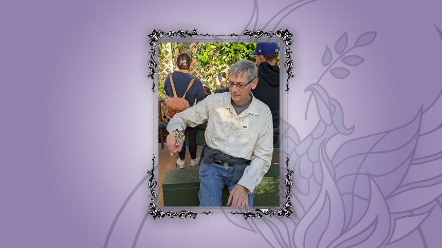 UUCP Member Gary Ezzell sitting outdoors with a butterfly perched on his finger